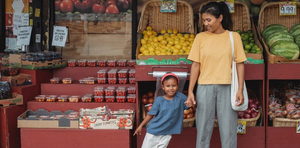 -Mother and daughter buying fresh fruit at market.