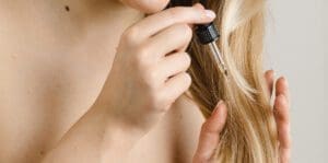 Hair Care Routine for Hair Growth. Woman using hair oil on split ends.